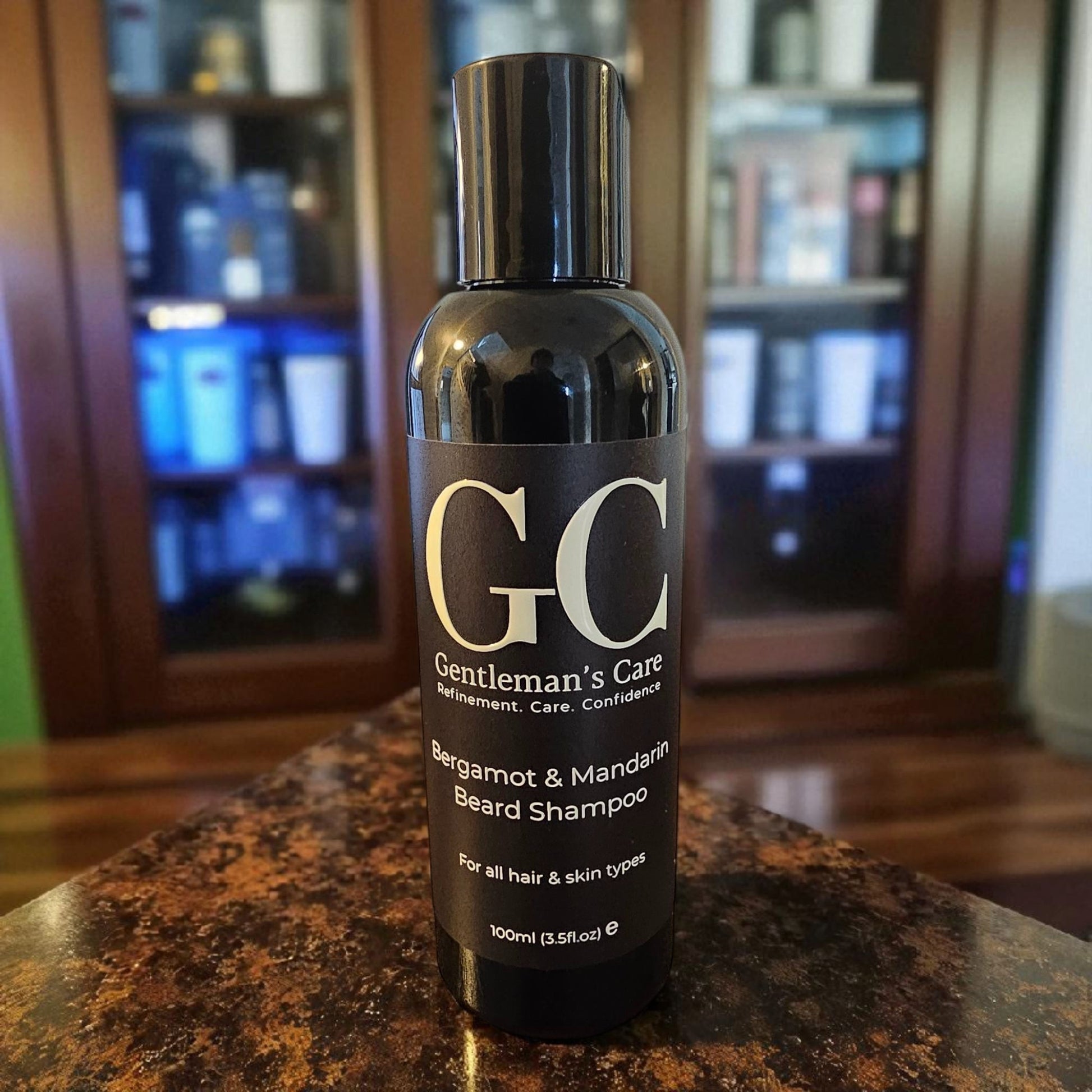 Bottle of Gentleman's Care beard shampoo on a marble surface with a blurred background