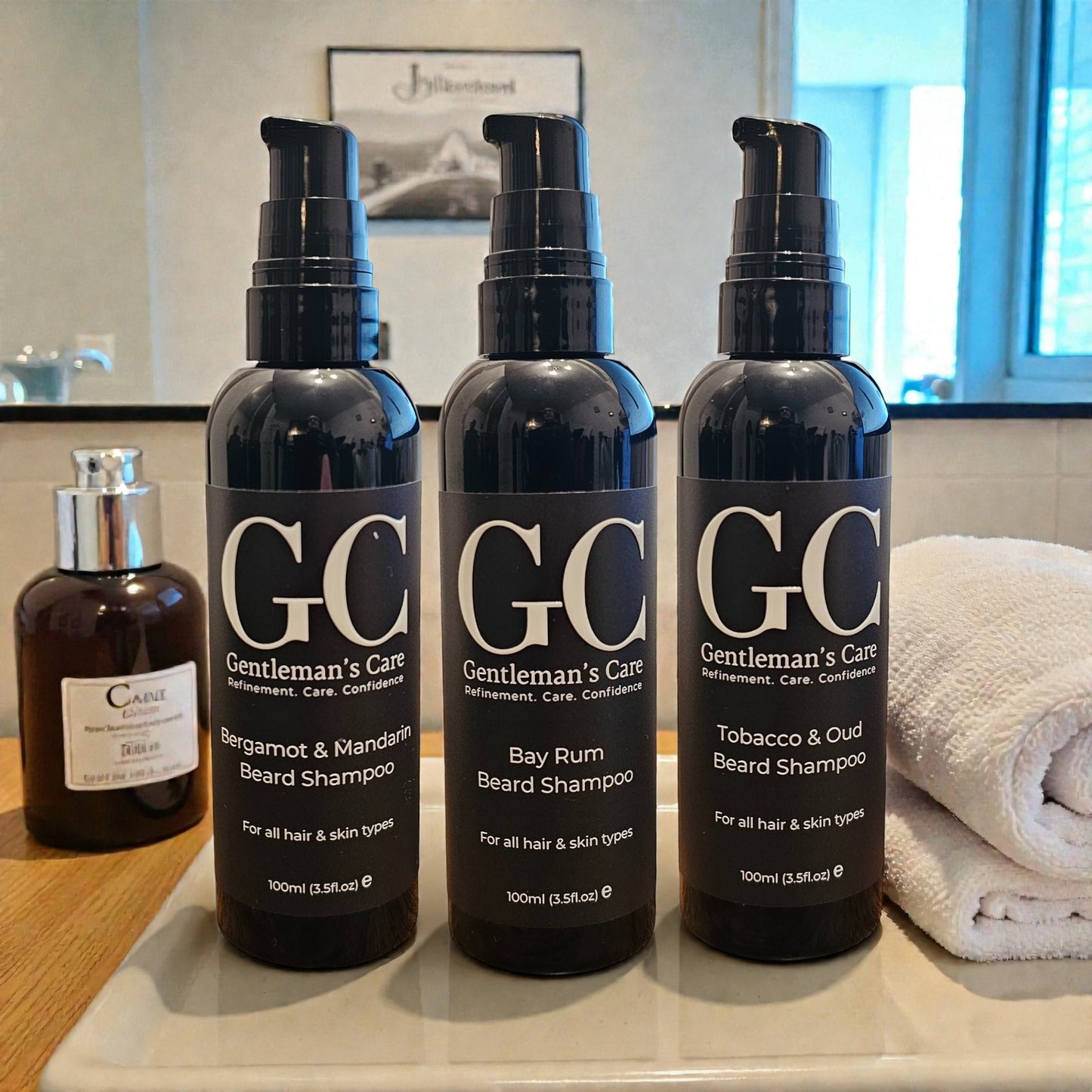 Three bottles of Gentleman's Care beard shampoo on a bathroom counter with a towel and another bottle in the background.